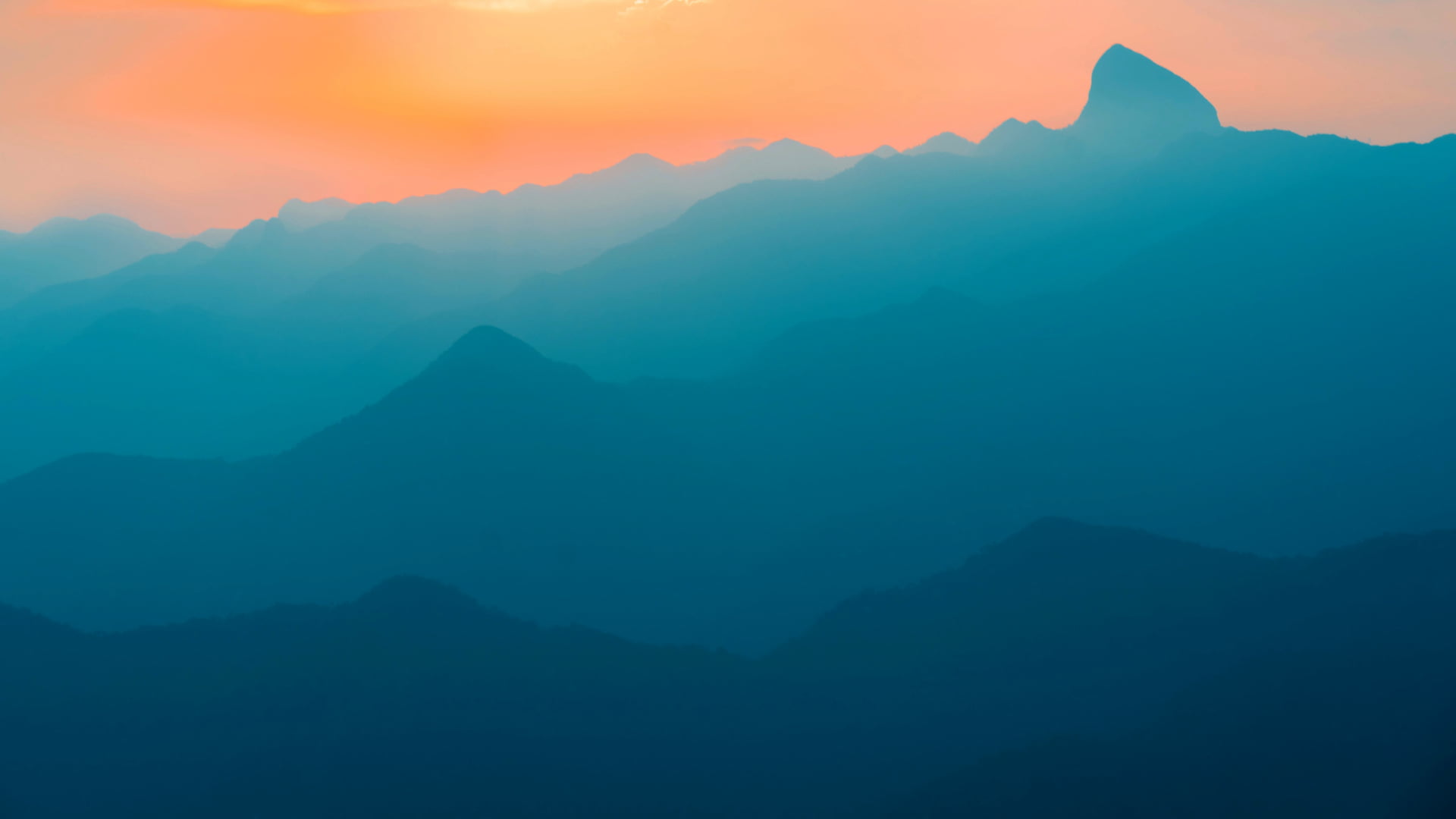 paysage de montagne bleutées avec un soleil rouge orange